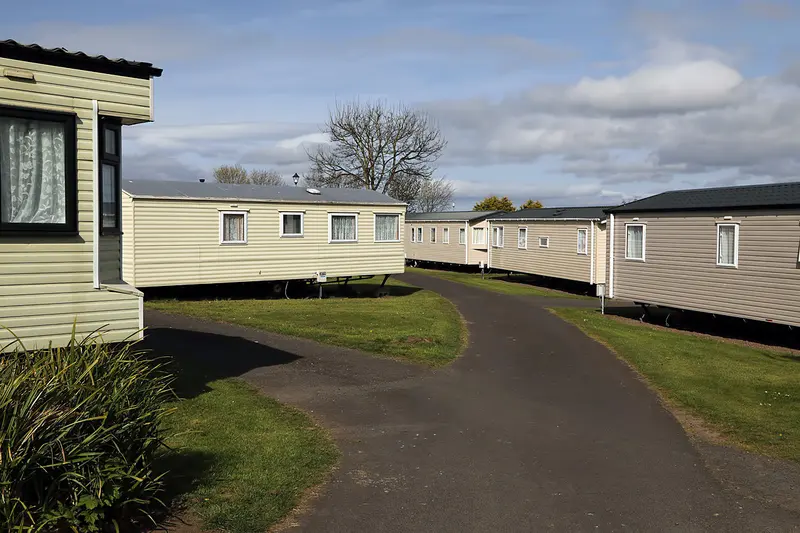 Cream static caravans lining a curving tarmac path on a holiday park